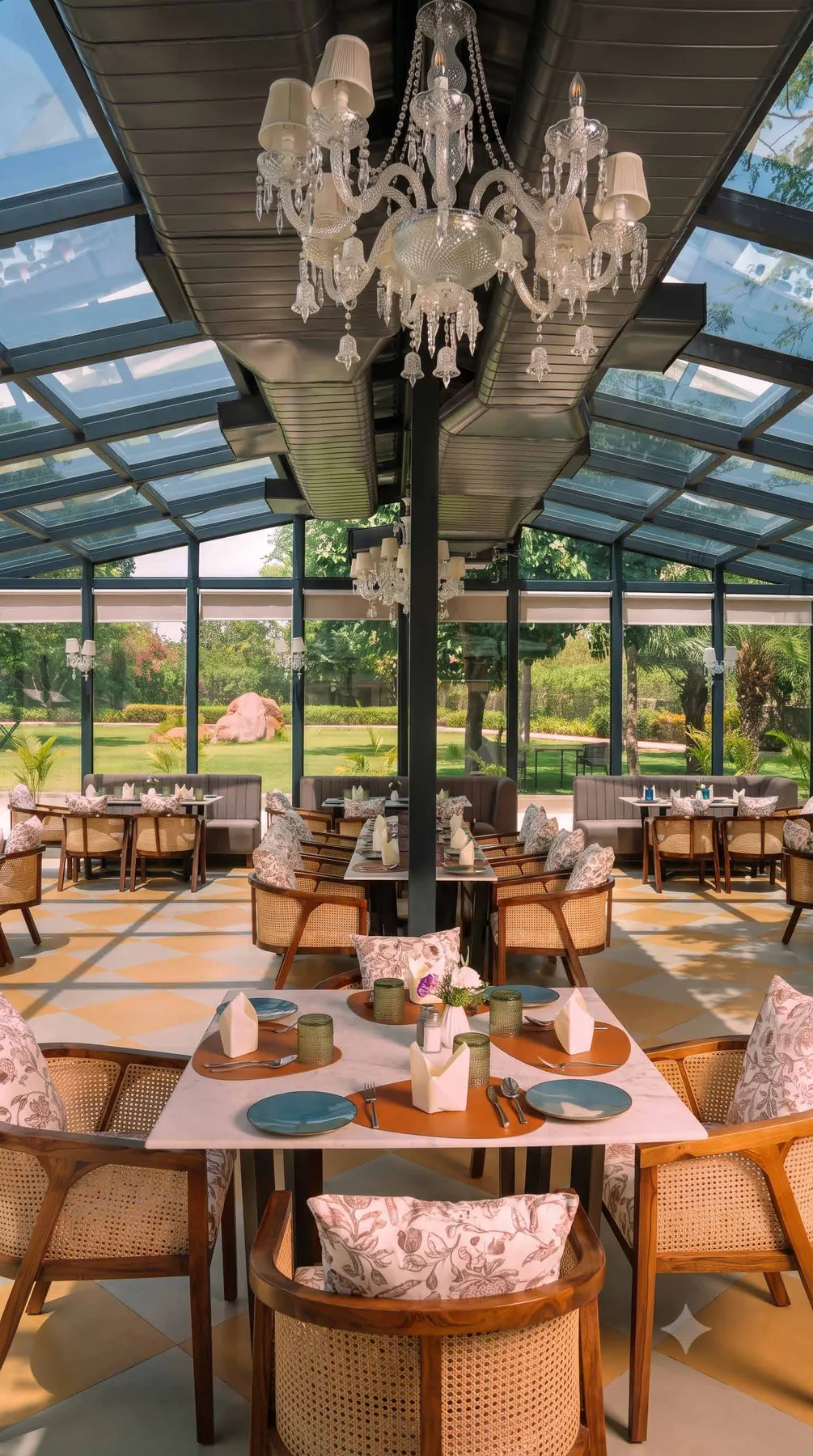 Inside The Glasshouse, chandeliers above cane chairs and marble tables